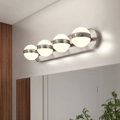 The Artika Baldric LED modern bathroom vanity light 3 CCT, featuring four frosted glass globes and metallic accents, is mounted above a large mirror with wood paneling and a green plant nearby.