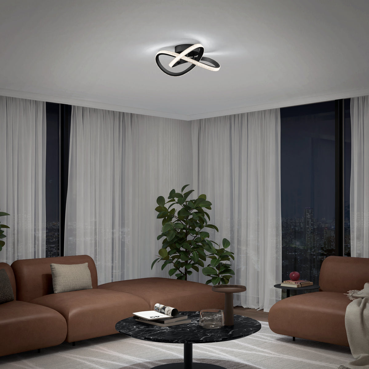 A modern living room at night with brown sofas, a round black coffee table, potted plants, large windows with curtains, and a contemporary ceiling light fixture with curving, illuminated bands.