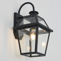 The Artika Colonial outdoor lantern wall light features clear glass panels and an exposed bulb, shown mounted on a white wall.