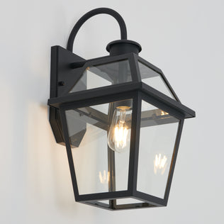 The Artika Colonial outdoor lantern wall light features clear glass panels and an exposed bulb, shown mounted on a white wall.