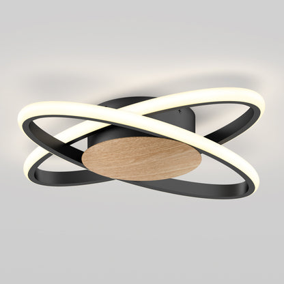 The Artika Atomic 15 in. LED flush mount light features two intersecting black rings with integrated LEDs, set on a round wooden base—all against a light gray background. Adjustable to 5 CCTs.