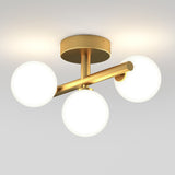 A modern ceiling light fixture with a gold base and three frosted white glass globes, arranged in a triangular pattern, mounted on a white ceiling.