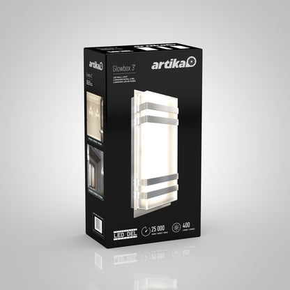 A black box packaging for the Artika Glowbox 3 LED wall light, showing an image of the modern rectangular fixture, key features like 25,000-hour lifespan, and icons for energy efficiency and brightness.