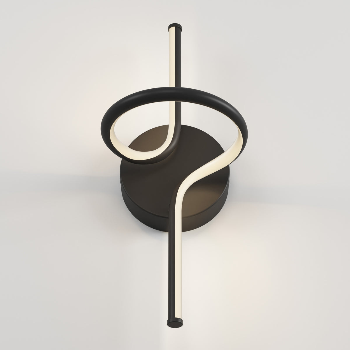A modern wall light fixture with a circular black base and a looping, curved LED light tube that forms a twisting, abstract shape against a plain white wall.