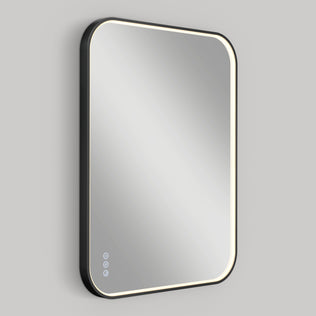 The Artika Royce Dimmable LED Mirror features a rectangular design with rounded corners, 3 CCT options, a glowing LED border, and three touch controls on the lower left, shown wall-mounted horizontally against a plain gray background.
