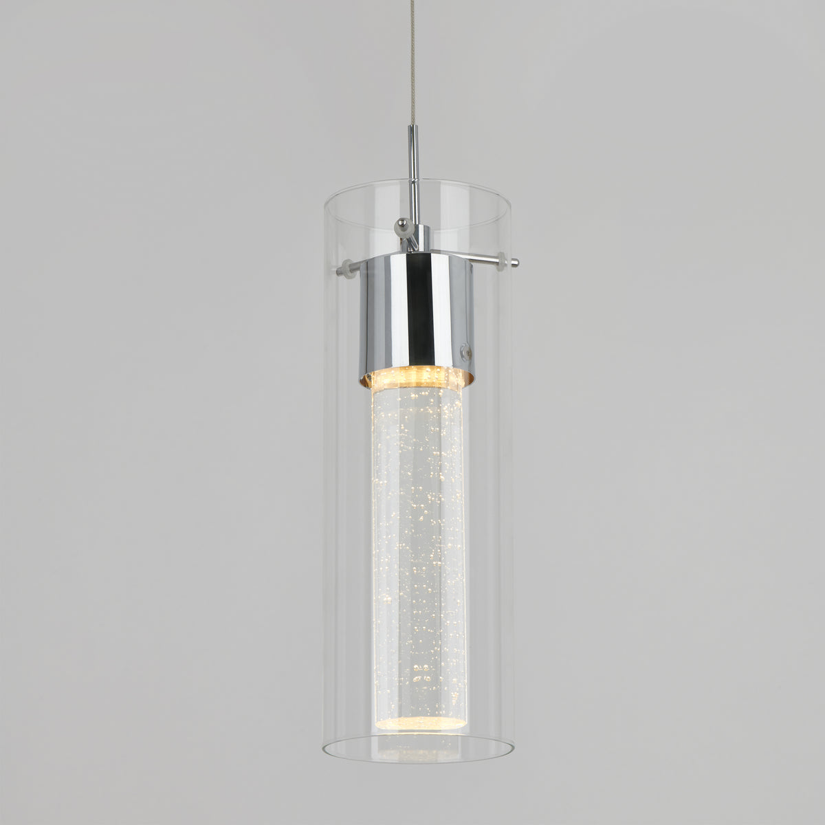 A modern pendant light with a cylindrical clear glass shade and a chrome fixture, featuring an illuminated inner tube with small bubbles, suspended against a plain light gray background.