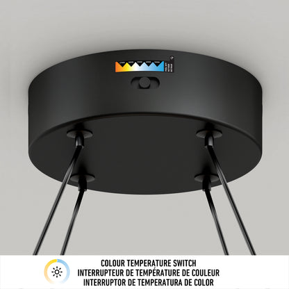 Close-up view of a black ceiling light fixture with a color temperature switch, labeled with different color temperatures, and three supporting rods. Text below describes the switch in English, French, and Spanish.