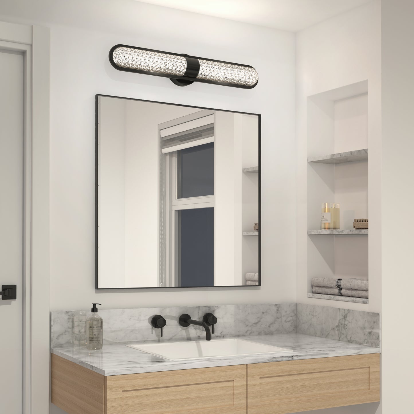 A modern bathroom features a marble countertop, rectangular sink, black faucet, and wall-mounted mirror. Above is the Artika Carat LED contemporary bathroom vanity light 3 CCT. Shelves hold folded towels and a soap dispenser.