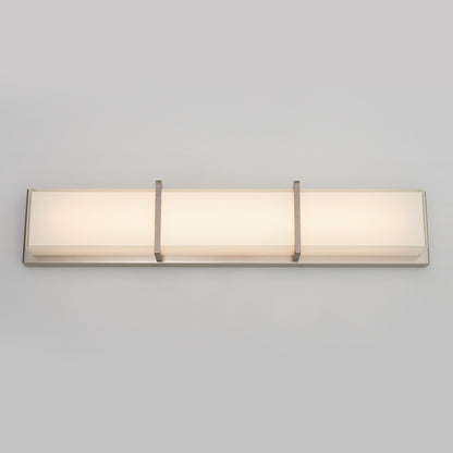 The Artika Subway LED bathroom vanity light features a modern rectangular design with a frosted white panel, metallic silver frame, and three vertical metal bands, shown mounted on a plain light gray wall.