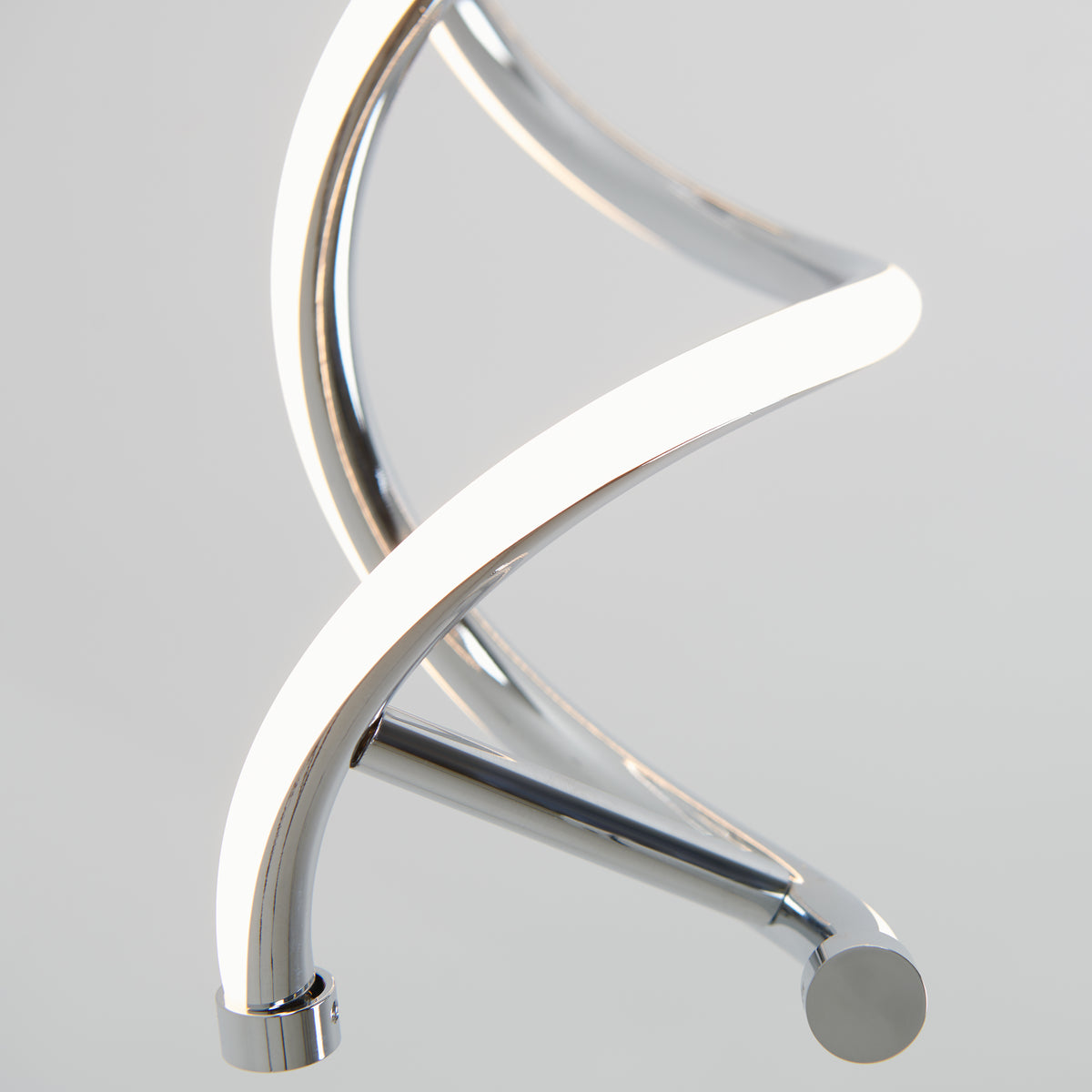Close-up of the Artika DNA LED pendant light, featuring a sleek chrome finish and integrated LEDs glowing along its spiral structure, set against a plain light gray background.