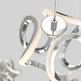 Close-up of a modern, abstract chandelier with curved, metallic and white LED light elements suspended from a ceiling, set against a neutral gray background.