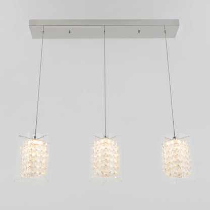 The Artika Crystal Cube 3-light LED pendant light features three crystal cube shades hanging in a row from a rectangular metallic mount, suspended by thin cables against a plain light gray background.