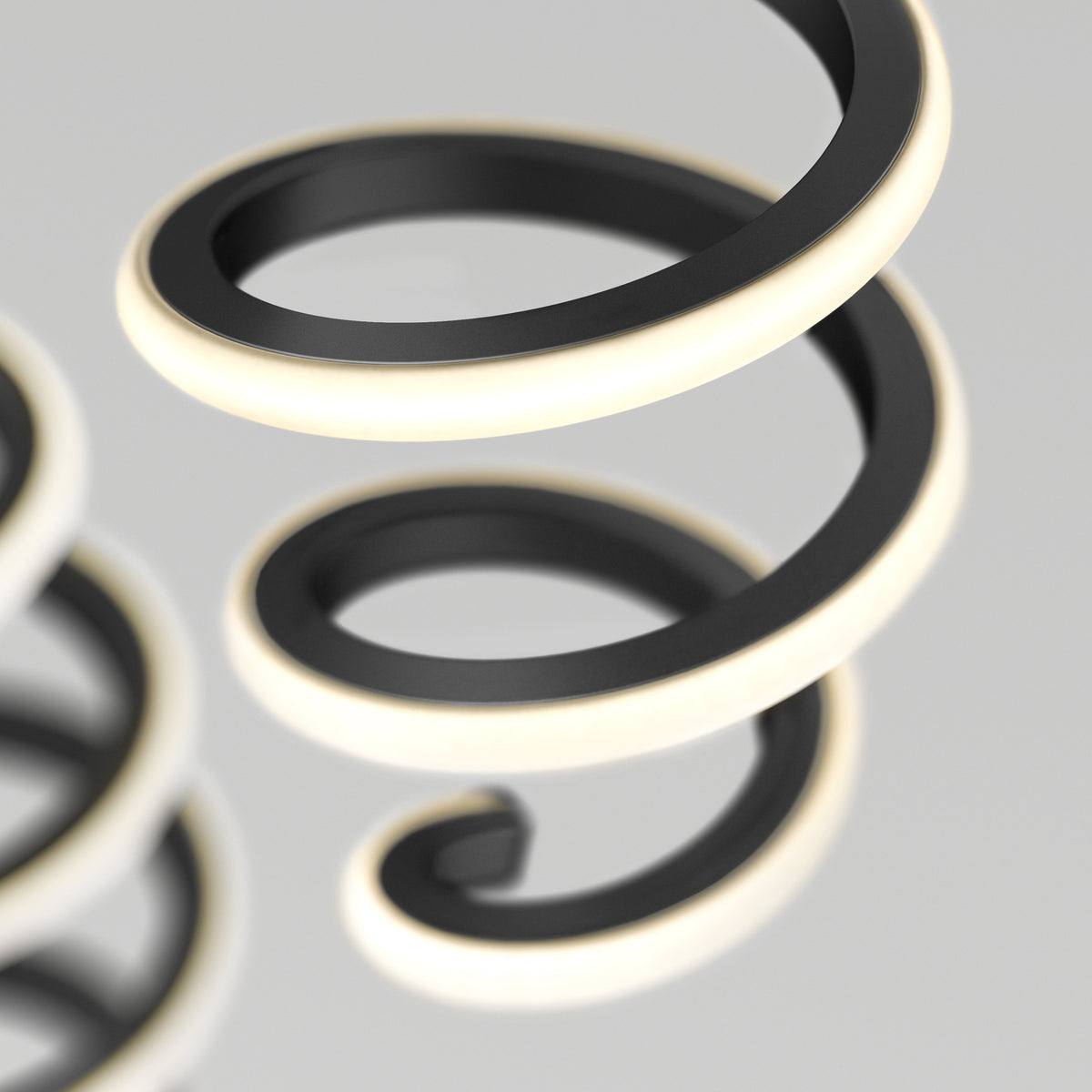 A close-up of two black metallic spiral coils with glowing white edges, set against a soft gray background. The focus is on the curves and illumination of the spirals.