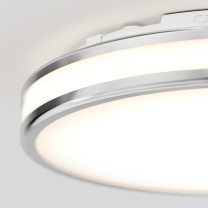A close-up of the Artika Hemisphere 15 in. LED flush mount light 5 CCT, a modern fixture with chrome accents and adjustable color temperature, emitting soft white light and mounted on a pale ceiling.