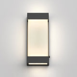 A modern rectangular wall light with a dark frame and a frosted white center, mounted on a light gray wall and emitting a soft glow.