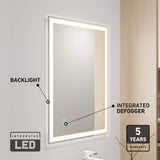 A rectangular bathroom mirror with a glowing LED backlight and an integrated defogger, mounted on a light-colored wall. Text highlights features: Backlight, Integrated Defogger, Integrated LED, and 5 Years Warranty.