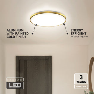 The Artika Europa 21 in. LED modern flush mount light, with a gold-painted aluminum finish, is mounted on a white ceiling above a dark door. It features energy efficiency, an integrated LED, remote control, and a 3-year warranty.