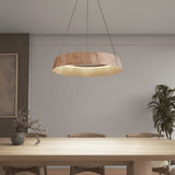 A modern dining room with a wooden table, four chairs, a vase with branches, a large round wooden pendant light, a potted plant, and a framed artwork on the wall.