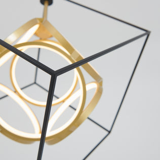 The Artika Luxury LED pendant light displays intersecting black metal cubes and glowing gold rings, offering a modern geometric design that creates an artistic focal point against any plain background.