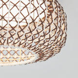Close-up of a woven rattan lampshade with a geometric pattern, illuminated from within, against a plain light background.