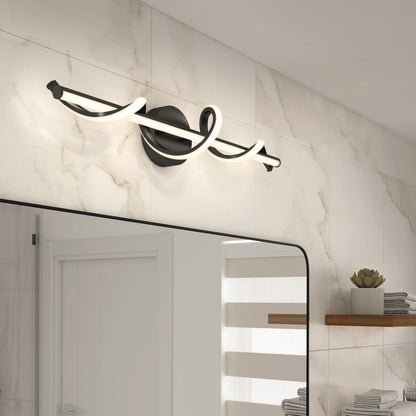 A modern bathroom displays the Artika Coda modern LED bathroom vanity light 5 CCT, in black and white, mounted above a large mirror. Beige marble tiles, a wooden shelf with a potted plant, and a white door reflected in the mirror complete the look.