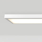 A rectangular, modern ceiling light fixture glows with a soft white light against a plain white ceiling.