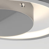 Close-up of a modern, circular ceiling light with a metallic finish and a soft, white LED glow around the edge. The design is sleek and minimalistic.