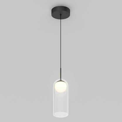 The Artika Mirah LED modern mid-century pendant light 3 CCT features a black ceiling mount and cord with a clear cylindrical glass shade around a glowing bulb, set against a plain light gray background.