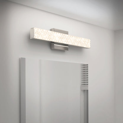 The Adeline modern LED bathroom vanity light 3 CCT by Artika, featuring a textured rectangular design, is mounted above a large mirror on a white wall, providing a soft and even illumination.