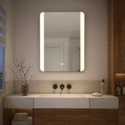 Modern bathroom with Artika Onyx 24″x32″ dimmable LED mirror, minimalist sink, towels, soap dispenser, and a branch-filled vase.