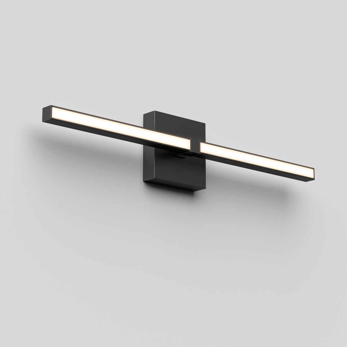 A modern, minimalist wall-mounted LED light fixture with a horizontal rectangular bar emitting white light, attached to a square black base on a plain light gray wall.
