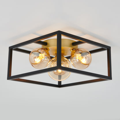 The Artika Griffintown flush mount is a modern ceiling light with three exposed round bulbs in a square black metal frame and gold base, shown mounted on a white ceiling.