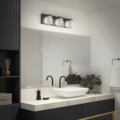 A modern bathroom features a white vessel sink, black faucet, marble countertop, mirror, and the Artika Crystal Cube LED bathroom vanity light 5 CCT above. Dark cabinets, a towel holder, and a vase of purple flowers sit beside the sink.