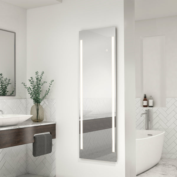 A modern bathroom with the Artika-CAN-dev Emeraude Full Length Mirror featuring vertical LED lights, a freestanding bathtub, a wooden vanity with sink, and green branches in a vase.