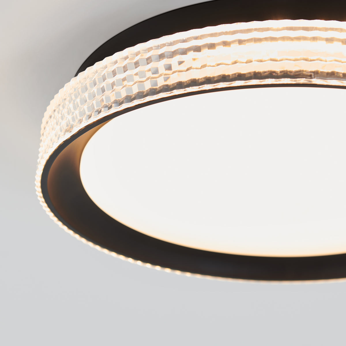 Close-up of the Artika Aston 15 in. LED modern flush mount light 5 CCT, featuring a textured, translucent outer ring and smooth, glowing LED center, mounted on a white ceiling.