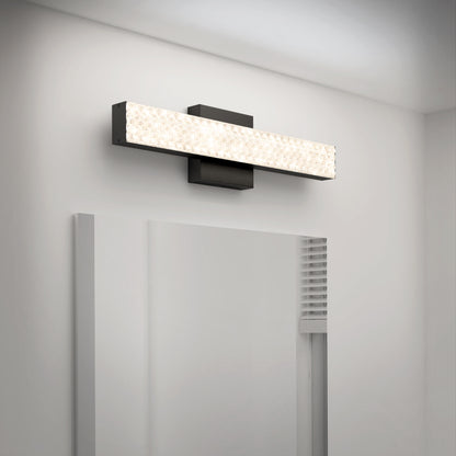 The Adeline modern LED bathroom vanity light by Artika, featuring a textured illuminated panel and 3 CCT settings, is mounted above a mirror on a white wall, creating a bright and clean bathroom ambiance.