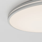 Close-up of a modern, circular ceiling light fixture with a smooth, white diffused cover and a thin gray trim, mounted on a white ceiling.