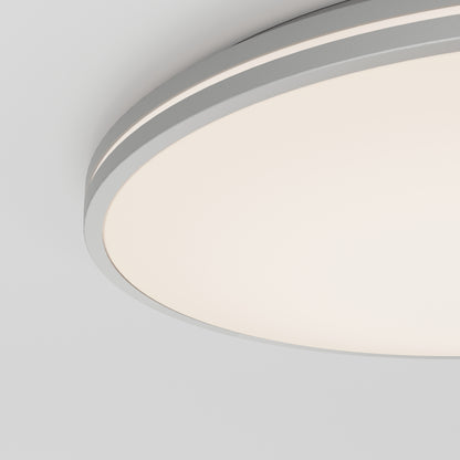 A close-up view of the Artika Athos 21 in. LED flush mount light with remote, featuring a smooth white diffuser and sleek gray rim, mounted on a white ceiling.