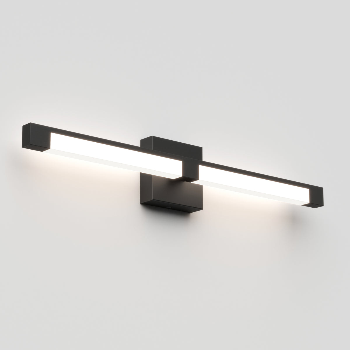 A modern wall-mounted light fixture with a long horizontal rectangular LED bar and a central black mounting base, emitting a bright white light against a plain white wall.