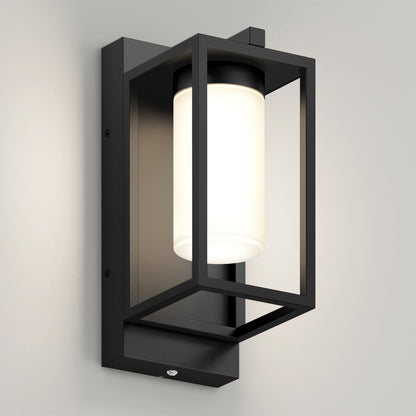 The Artika Aurel Outdoor LED Light, 3CCT is a modern black wall sconce featuring a rectangular frame and cylindrical frosted glass, shown mounted on a light-colored wall.