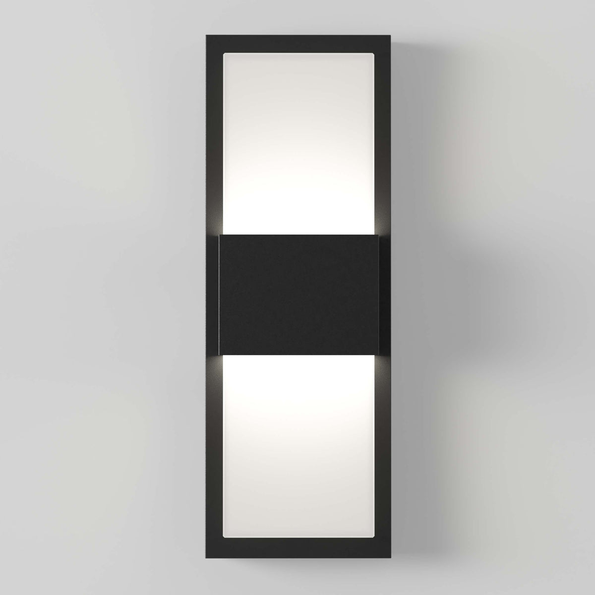 A modern rectangular wall sconce with a black frame and a central black panel, emitting soft white light from both the top and bottom sections, mounted on a light grey wall.