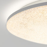 Close-up of a modern round ceiling light with a textured, frosted glass cover emitting a soft, warm glow against a white ceiling.