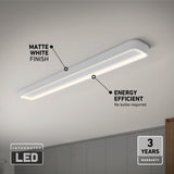 A rectangular matte white LED ceiling light is mounted on a white ceiling above a modern room. Text highlights its matte finish, energy efficiency, integrated LED, and 3-year warranty.