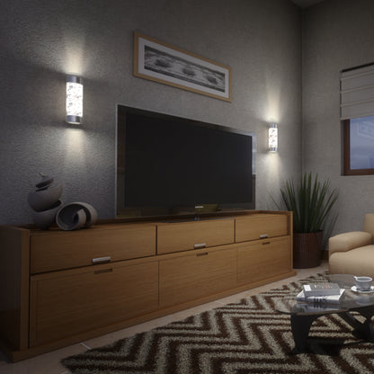 A modern living room featuring a flat-screen TV on a wooden cabinet, abstract decor, a Bubble Element LED indoor-outdoor light by Artika, zigzag rug, glass coffee table with magazines, plant, and beige armchair near a window with blinds.