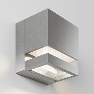 The Artika Valor Square LED indoor-outdoor wall light features a modern square design with a brushed metal finish and clear glass panels, emitting soft, dimmable LED light from top and bottom—ideal for enhancing any white wall.