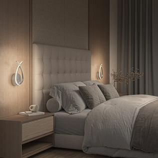 A modern bedroom features a large upholstered headboard, neutral bedding with textured pillows, matching wooden nightstands, and Artika’s Gamma modern LED wall sconces (5 CCT). A small vase with branches adds an extra stylish touch.