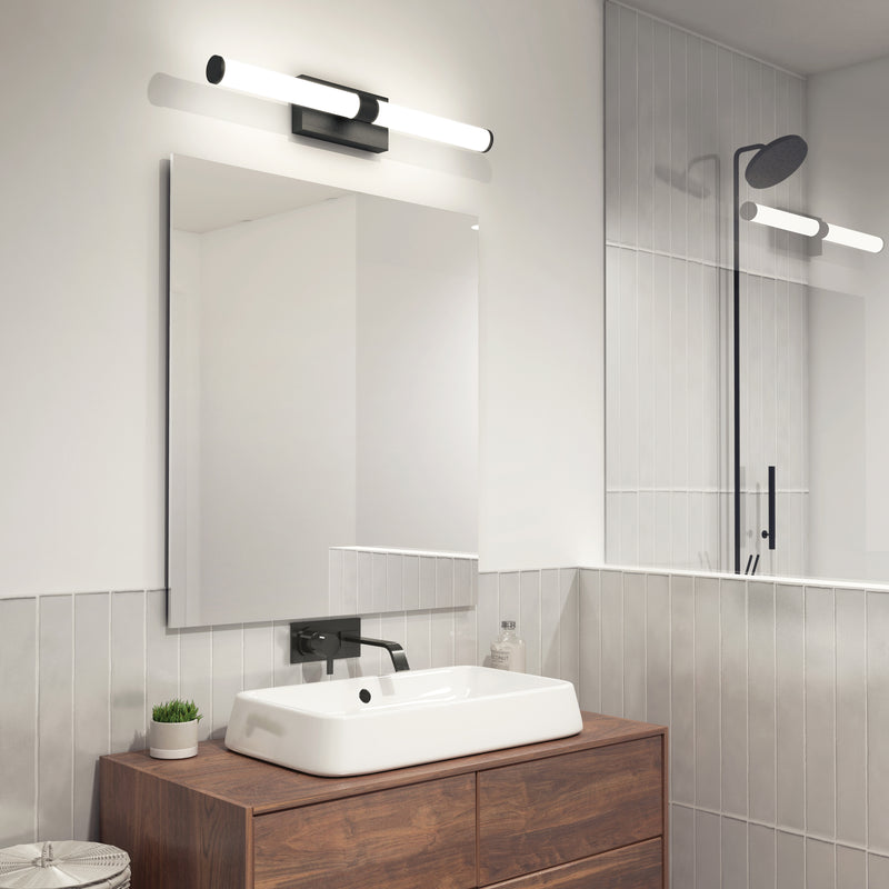 Modern bathroom with a rectangular mirror above a wooden vanity, white sink, and black fixtures. Above the mirror is the Artika Vitoro modern LED bathroom vanity light, and a glass-enclosed shower with rain showerhead is visible.