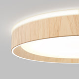 A close-up of a modern ceiling light fixture with a circular design, featuring a wood-textured outer rim and a bright white illuminated center against a neutral gray background.