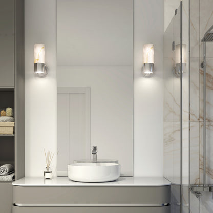 A modern bathroom showcases a round white vessel sink on a sleek vanity, flanked by two Artika Marble LED contemporary sconces. A glass shower and neatly folded towels complete the clean, minimalist space.