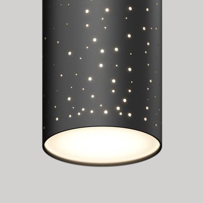 The Artika Cosmic modern LED pendant light 3 CCT features a black cylindrical design with small circular cut-outs, projecting a starry effect and a warm glow from its open bottom against a plain gray background.